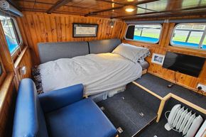 Cozy interior of a 1921 Classic Dutch Barge with wooden paneling and a comfortable bed.