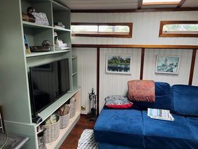 Cozy interior of a 1901 Classic Dutch Barge with blue sofa and wall art.