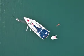 Aerial view of 2013 Beneteau Oceanis 41 sailboat with swimmer and dinghy in turquoise water.