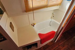 Interior of a 1927 Classic Dutch Barge featuring a cozy bathtub with red towel.