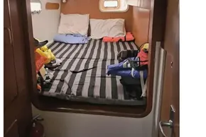 Cozy cabin interior of 2008 Leopard 38 catamaran with striped bedding and porthole window.
