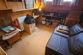 Cozy interior of a 1926 Dutch Barge Luxemotor with books, sofa, and storage boxes.