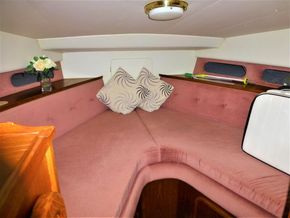 Cozy cabin interior of 1995 Aquafibre Bounty Boats 10/70 with pink upholstery and decorative pillows.