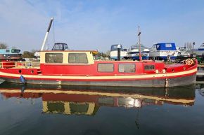 Classic 1927 Dutch Barge with red and cream exterior docked at a marina.