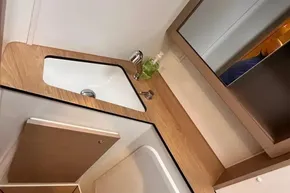 2024 Lagoon 42 bathroom sink with wooden countertop and mirror cabinet.