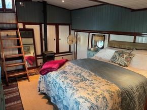Cozy bedroom in a 1901 Classic Dutch Barge with vintage decor and wooden ladder.