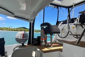 2024 Lagoon 42 yacht interior with ocean view and tropical island backdrop.