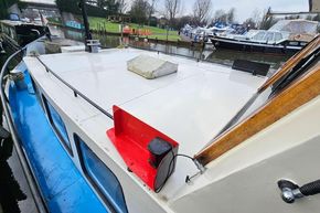 Classic 1921 Dutch Barge moored on a river, featuring a white deck and blue hull.