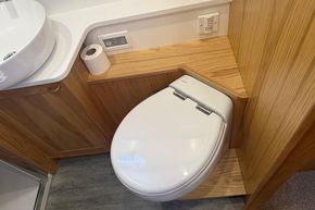 Modern bathroom with wooden cabinetry, featuring a sleek toilet and sink. Piper 12c, 2024 model.