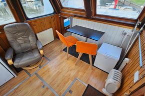 Interior of a 1921 Classic Dutch Barge with seating, table, and mini fridge.