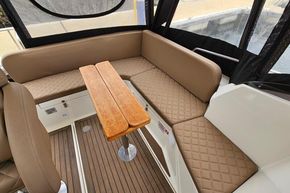 Interior of 2023 Balt 818 Titanium boat with brown quilted seating and wooden table.