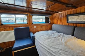 Cozy interior of a 1921 Classic Dutch Barge with wood paneling and a comfortable bed.