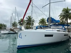 2019 Jeanneau Sun Odyssey 440 sailboat docked, surrounded by palm trees and calm water.