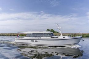 2025 Linssen 45 SL Sedan yacht cruising on a calm river under a clear sky.