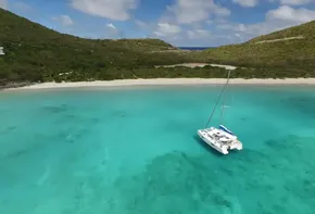 Lagoon 42 catamaran anchored in turquoise waters near a secluded beach, 2020 model.
