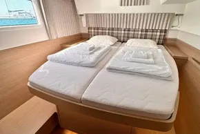 Luxurious cabin interior of 2024 Lagoon 42 catamaran with twin beds and nautical decor.