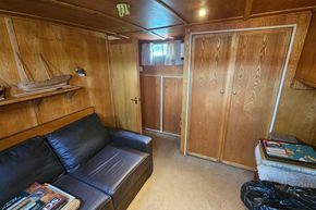Interior of a 1926 Dutch Barge Luxemotor with wooden paneling and a leather sofa.