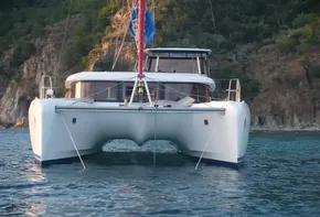 2020 Lagoon 42 catamaran anchored in serene waters with lush green hills in the background.