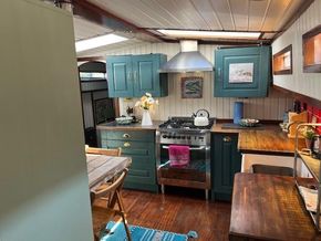 Cozy kitchen interior of a 1901 Classic Dutch Barge with teal cabinets and wooden countertops.