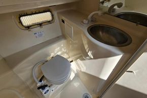 1998 Maxum 2400 SCR boat bathroom with sink, toilet, and porthole window.