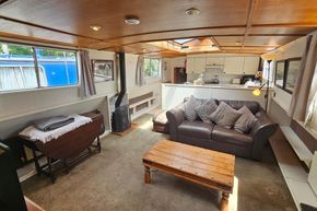 Cozy interior of a 1926 Dutch Barge Luxemotor with sofa, table, and kitchen area.
