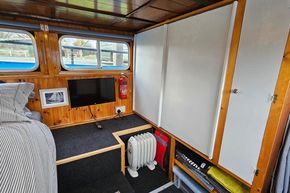 Interior of a 1921 Classic Dutch Barge with wood paneling, TV, and storage.