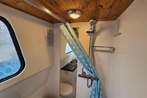 Bathroom interior of a 1921 Classic Dutch Barge with shower and wooden ceiling.