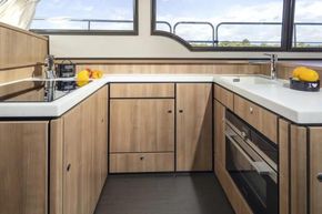 Modern kitchen interior of 2025 Linssen 45 SL Sedan yacht, featuring sleek wood cabinetry.