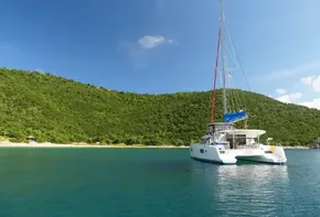 Lagoon 42 catamaran (2020) anchored in a serene tropical bay with lush green hills.