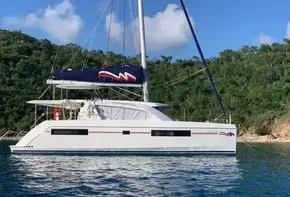 2020 Leopard 40 catamaran sailing in clear blue waters near a lush green coastline.