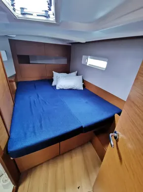 2020 Jeanneau Sun Odyssey 410 cabin with blue bedding and wooden interior.