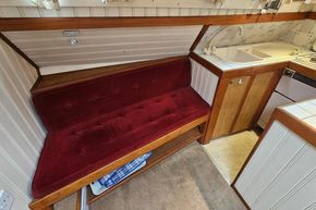 Cozy 1926 Dutch Barge Luxemotor interior with red velvet seating and compact kitchen area.