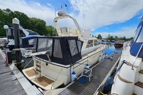 1989 Princess 35 Flybridge yacht docked at marina, featuring covered deck and clear skies.