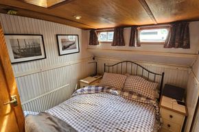 Cozy bedroom in a 1926 Dutch Barge Luxemotor with nautical decor and checkered bedding.