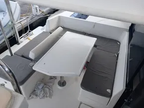 Outdoor seating area on a 2021 Leopard 40 catamaran with cushioned benches and table.