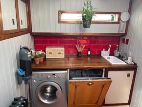 Cozy kitchen in a 1901 Classic Dutch Barge with red tiles and wooden accents.