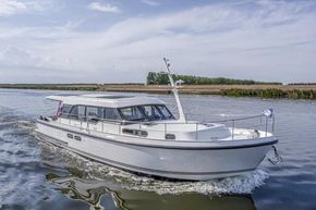 2025 Linssen 45 SL Sedan cruising on a serene waterway under a clear sky.