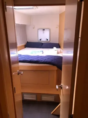 Cozy bedroom in a 2020 Lagoon 42 catamaran with a double bed and porthole.