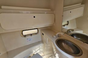 1998 Maxum 2400 SCR boat bathroom with sink, mirror, and porthole window.