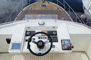 Flybridge helm of 1989 Princess 35 yacht with wooden deck and steering controls.