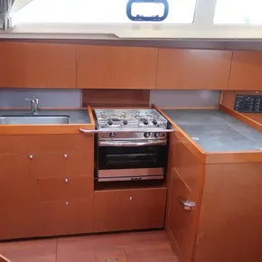 2019 Beneteau Oceanis 41.1 yacht kitchen with stove, sink, and wooden cabinetry.