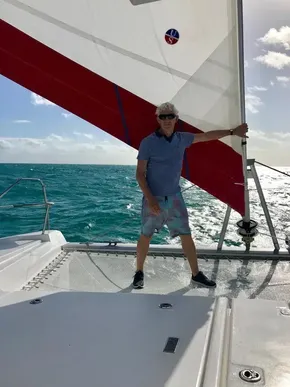 Man sailing on a 2020 Leopard 45 catamaran in sunny, turquoise waters.
