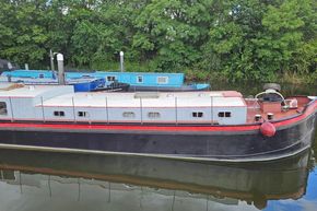 Vintage 1926 Dutch Barge Luxemotor on a serene river, surrounded by lush greenery.