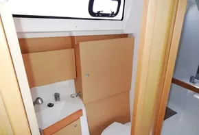 2017 Beneteau Oceanis 38 bathroom with wooden cabinets and white fixtures.