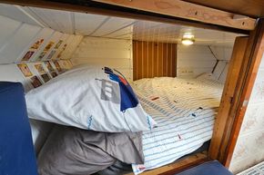 Cozy cabin bed in a 1921 Classic Dutch Barge with nautical-themed bedding.