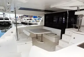 Spacious deck of 2017 Leopard 45 catamaran with seating and table, docked at marina.