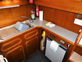 Compact kitchen area in a 1995 Aquafibre Bounty Boats 10/70, featuring a sink and mini fridge.