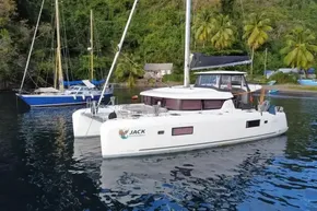 2024 Lagoon 42 catamaran anchored in tropical waters with lush greenery background.