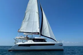 Sailing catamaran Leopard 42, 2022 model, gliding on open sea under clear blue sky.