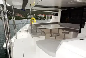 Leopard 50 yacht 2020 model, spacious outdoor seating area with table, docked near colorful buildings.